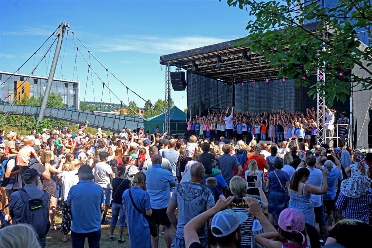 Utekonsert med mange publikummere i Mylderparken, Mailandbrua i bakgrunnen - Klikk for stort bilde