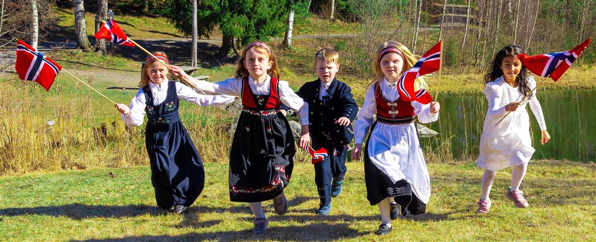 Fem barn med norske flagg og 17. mai klær løper mot kameraet - Klikk for stort bilde