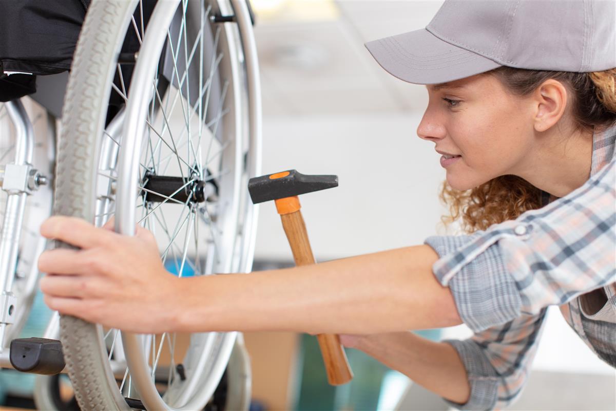 Bilde av dame som reparerer rullestol - Klikk for stort bilde