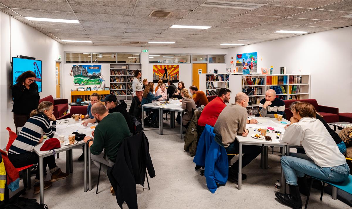 Voksne som diskuterer rundt småbord i bibliotek - Klikk for stort bilde