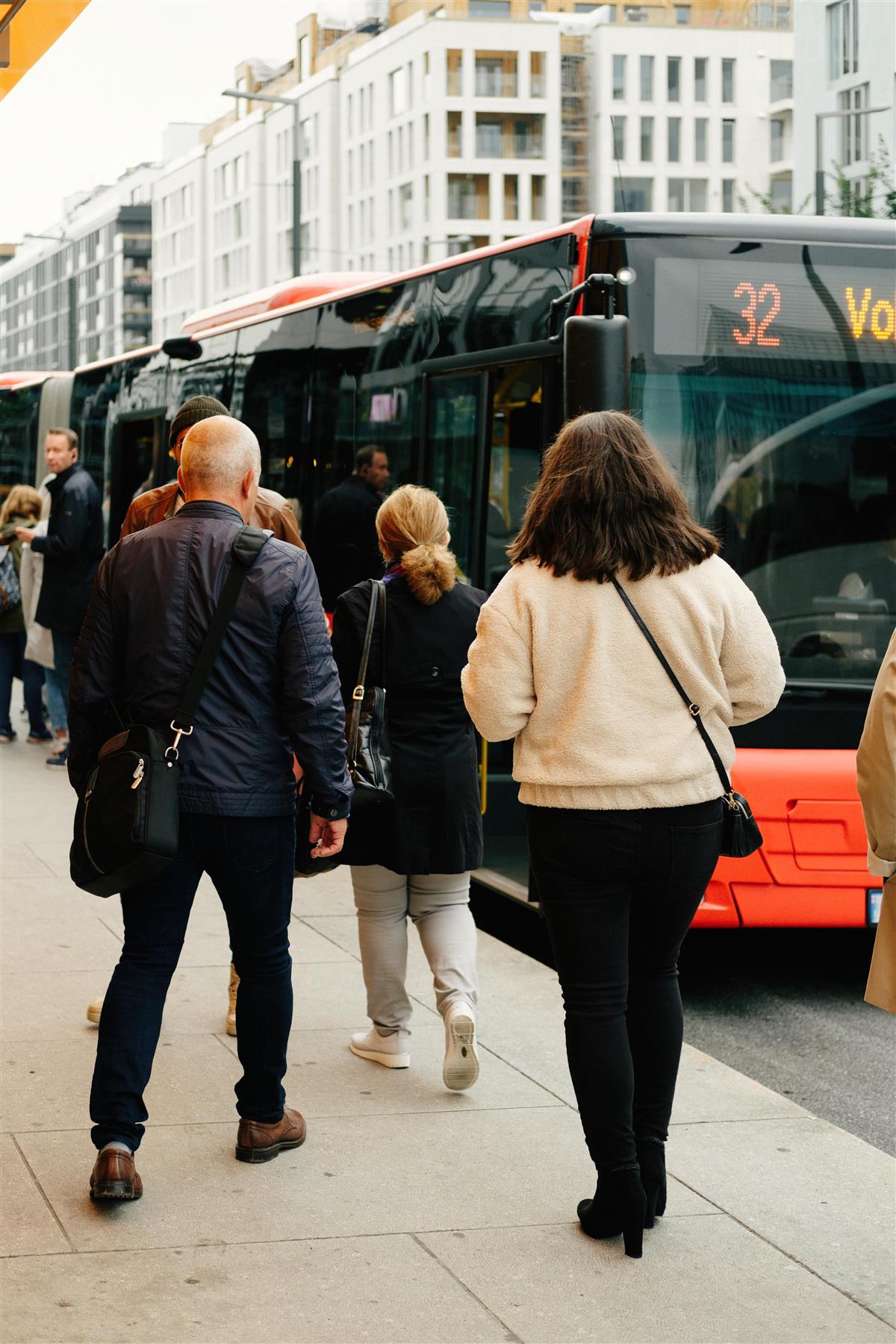 Flere personer går på en rød leddbuss - Klikk for stort bilde